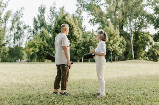 Smiling mature adults jogging together on outdoor trail in bright sunlight, demonstrating active healthy lifestyle