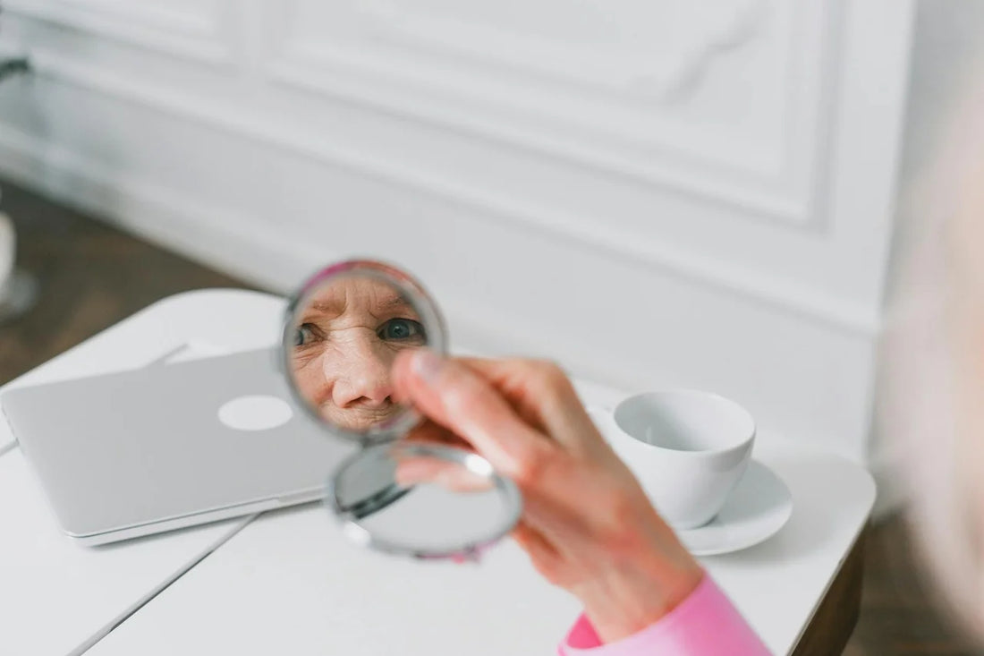 Exhausted person examining wrinkles and signs of aging while looking closely at their reflection in bathroom mirror