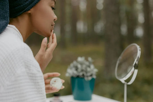 Woman gently applying facial moisturizer cream to her cheek as part of daily skincare routine
